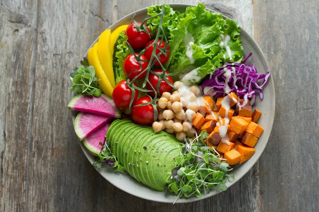 Bowl con palta en abanico, garbanzos, batata asada, tomates cherry, repollo morado y brotes