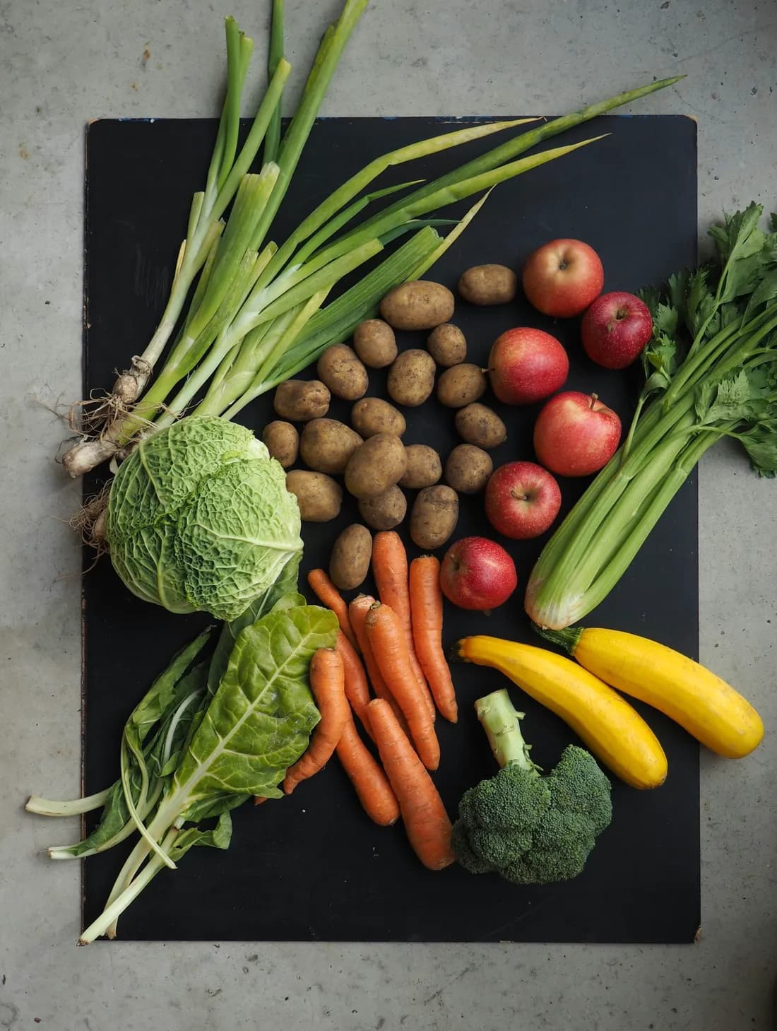 Repollo, zanahorias, apio, zucchini y brócoli sobre una tabla de pizarra
